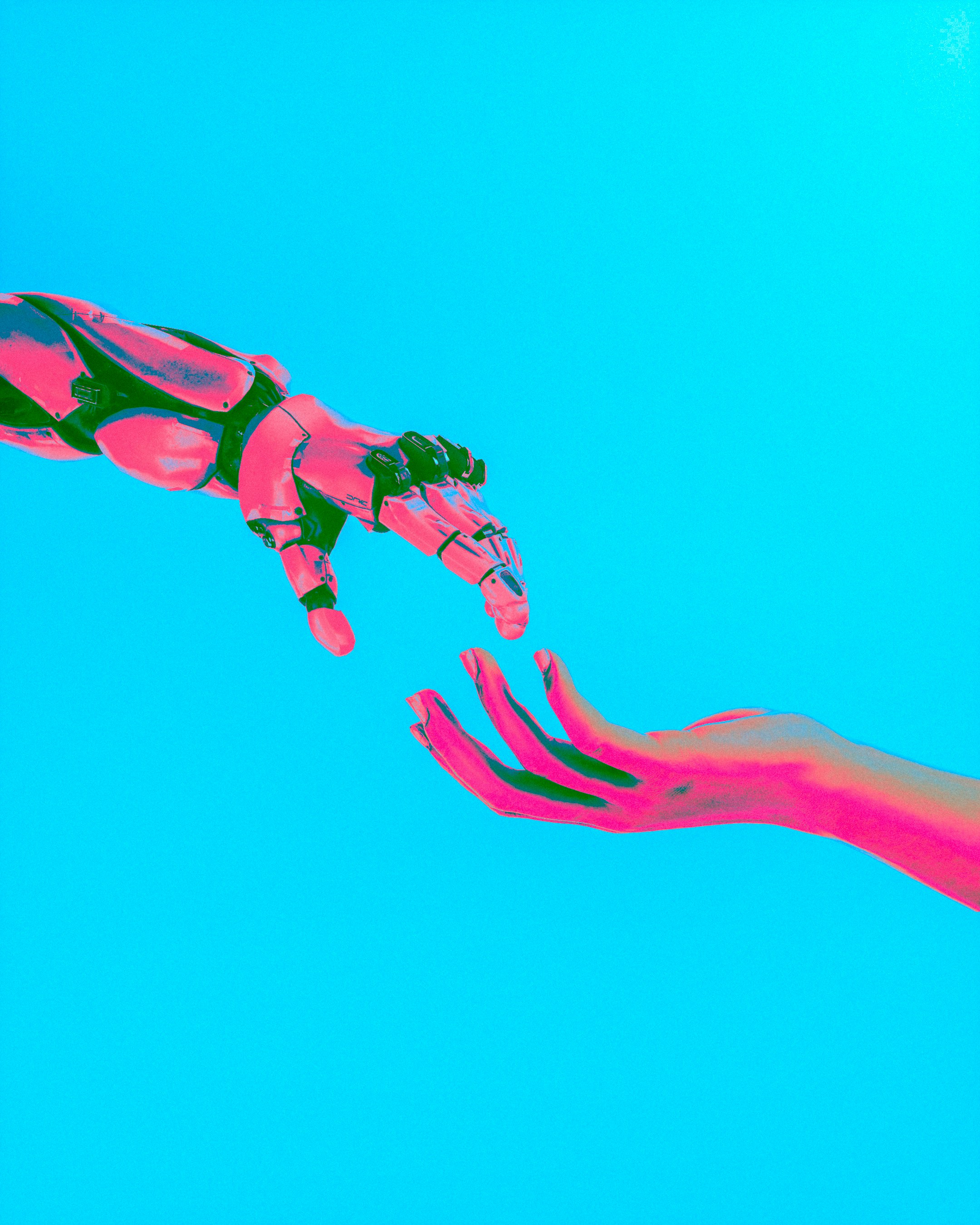 Robotic hand reaching toward a human hand on a cyan background — bridging AI and people.
